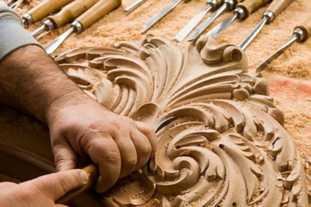 Geste d’un artisan travaillant le bois avec un outil manuel, montrant les traces laissées par la main et l’outil sur la matière