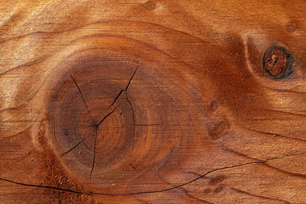Geste d’un artisan travaillant le bois avec un outil manuel, montrant les traces laissées par la main et l’outil sur la matière
